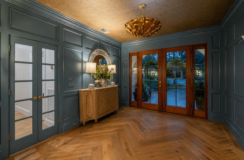 Entry vestibule finished in blue-grey wall panelling with French doors and a herringbone wood floor