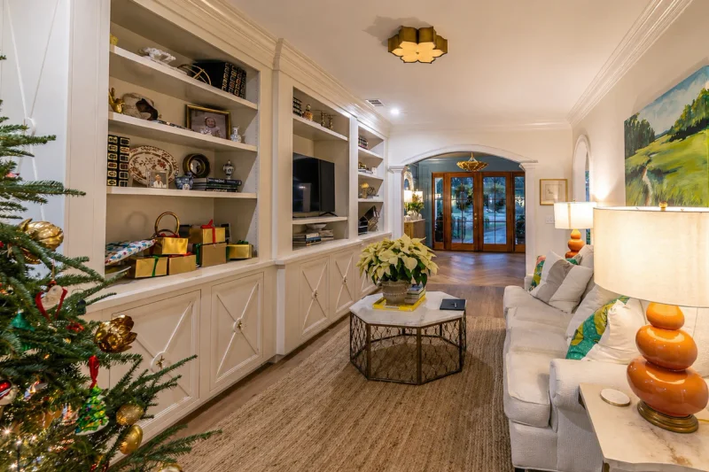 Living room with white painted built-in shelving and cabinetry beneath crown molding