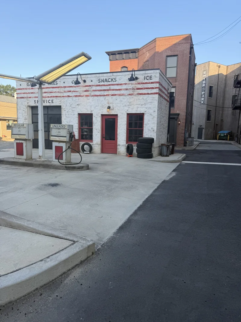 White commercial corner facade with red door openings viewed from the adjacent drive