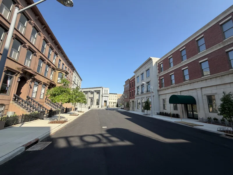 Street lined with brick and brownstone facades on a newly finished mixed-use block