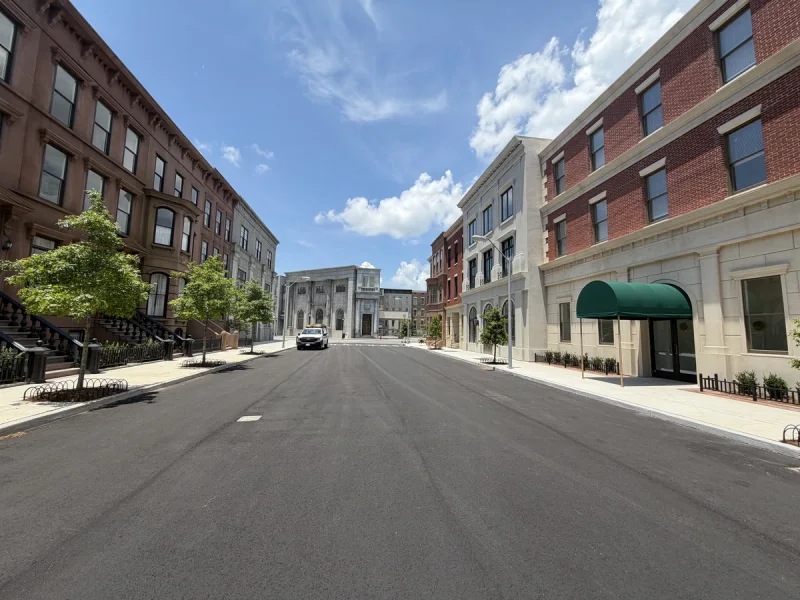 Wide street view of the finished mixed-use block with painted and brick facades