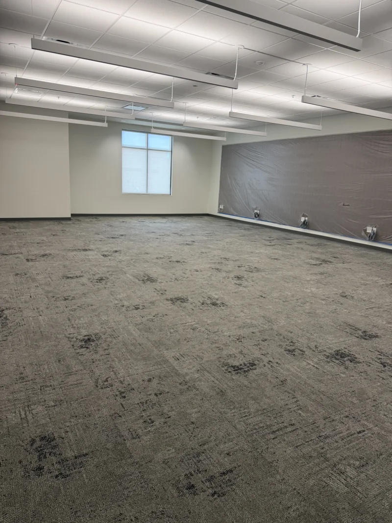 Open carpeted amenity room with painted walls and a dark accent wall