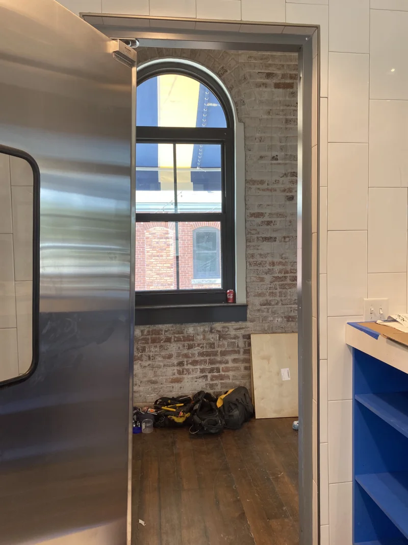 Tall arched window set into exposed brick above blue painted wall panelling