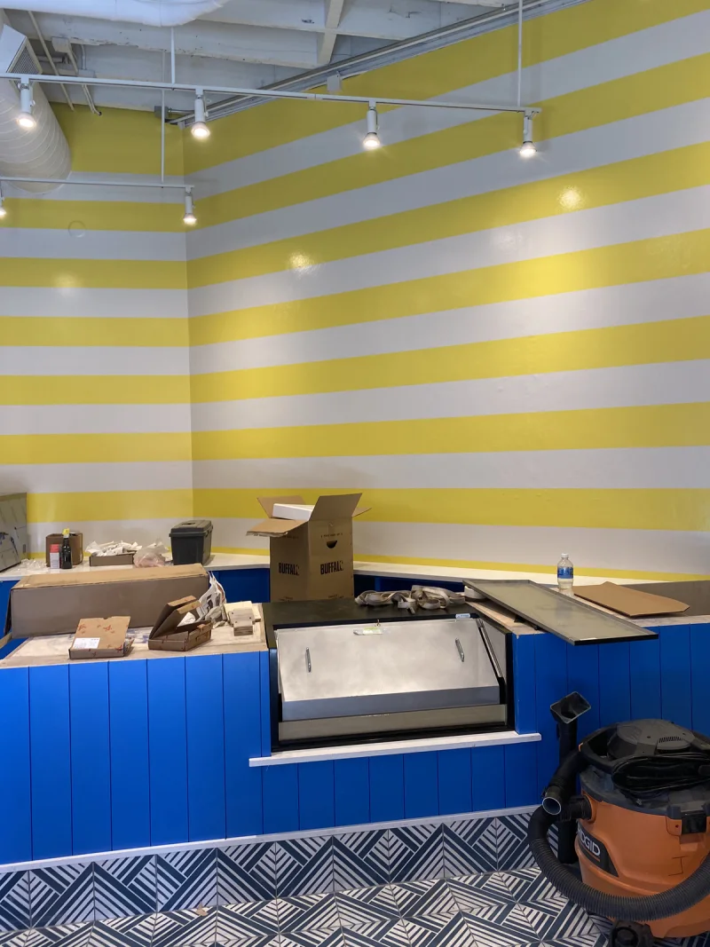 Yellow-and-white striped feature wall above a blue service counter during fit-out