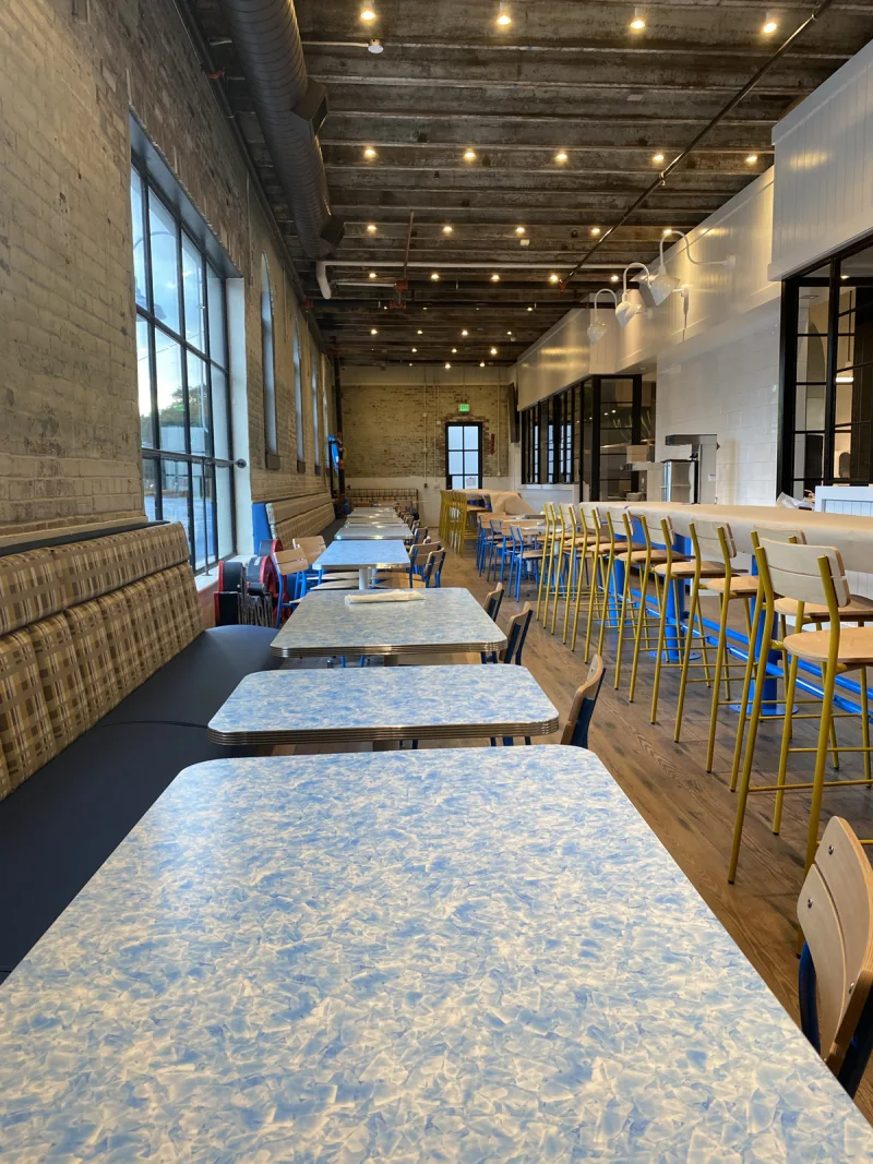 Café dining room with exposed brick walls, communal tables and blue painted accents