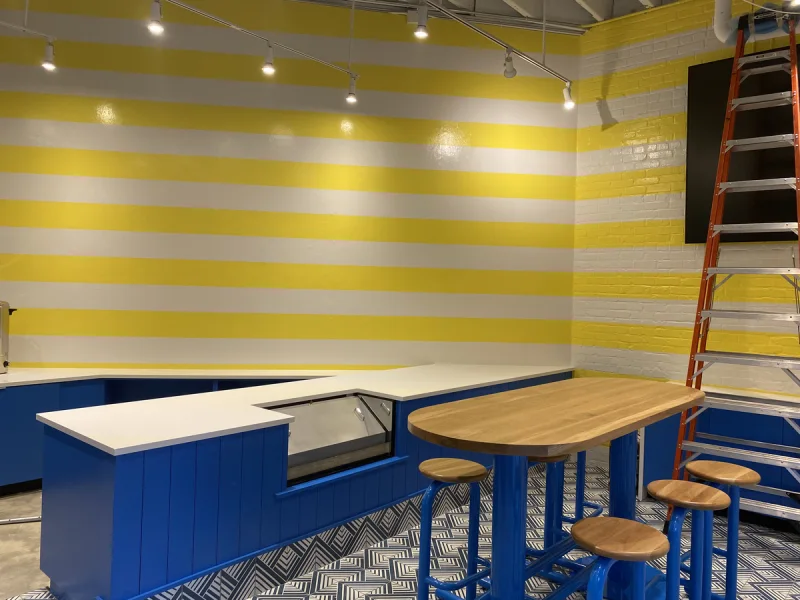 Service area with yellow-and-white striped walls above a blue painted counter and wood bar top