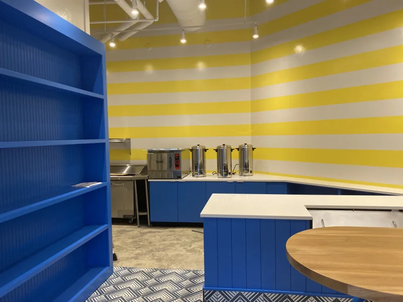 Blue painted shelving unit and counter set against a yellow-and-white striped wall