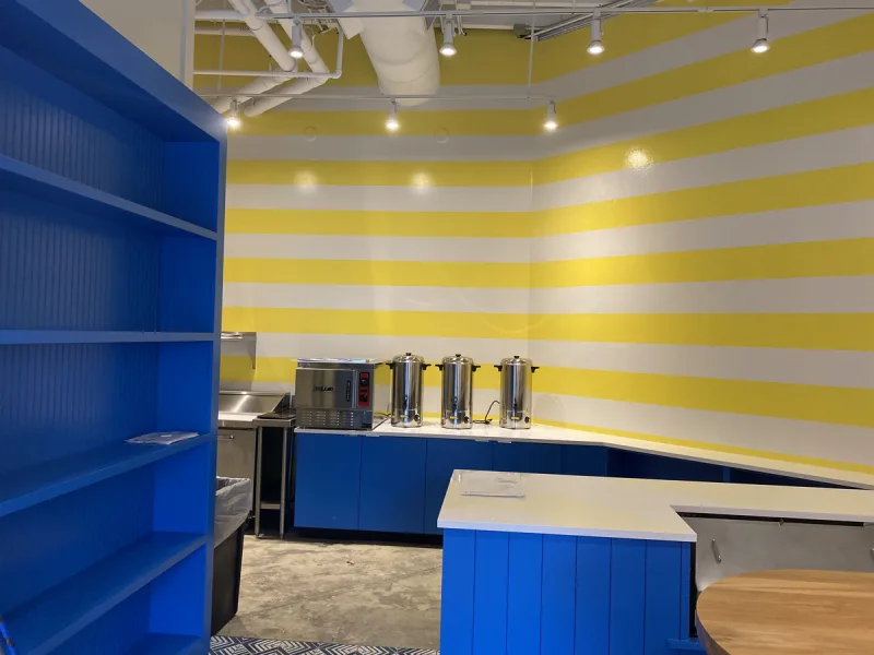 Blue display shelving and matching counter framed by yellow-and-white striped walls