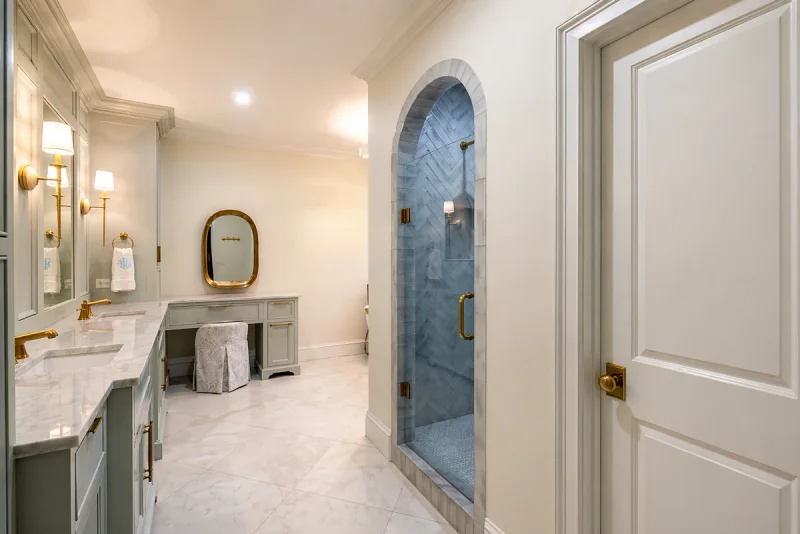 Bathroom with sage-grey painted vanity cabinetry beside an arched tiled shower