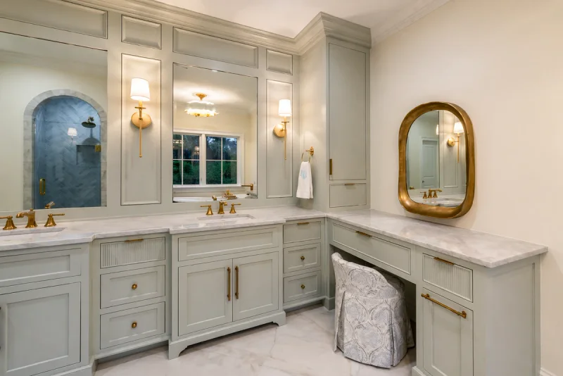 Corner vanity run painted in soft greige with marble tops and framed mirrors