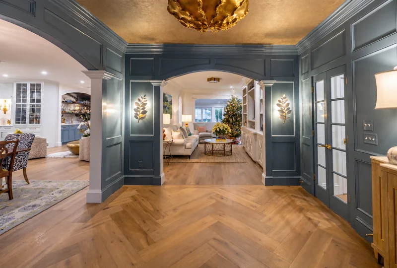 Paneled entry hall painted deep blue-grey, opening through a wide archway to a living room beyond
